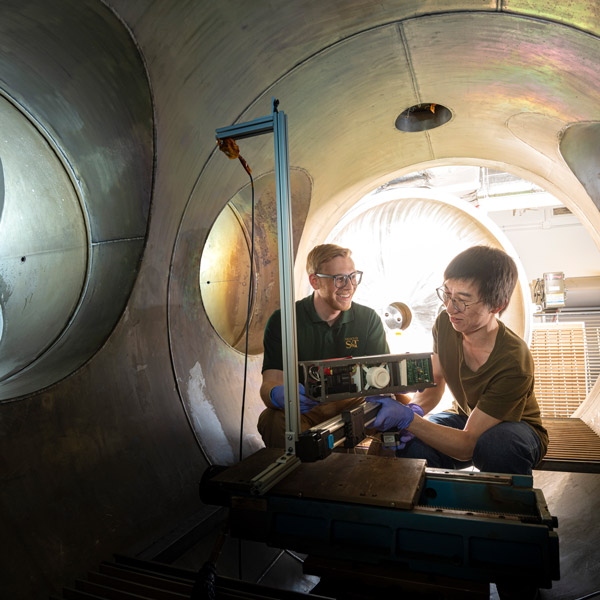 Two students sit inside a small chamber.