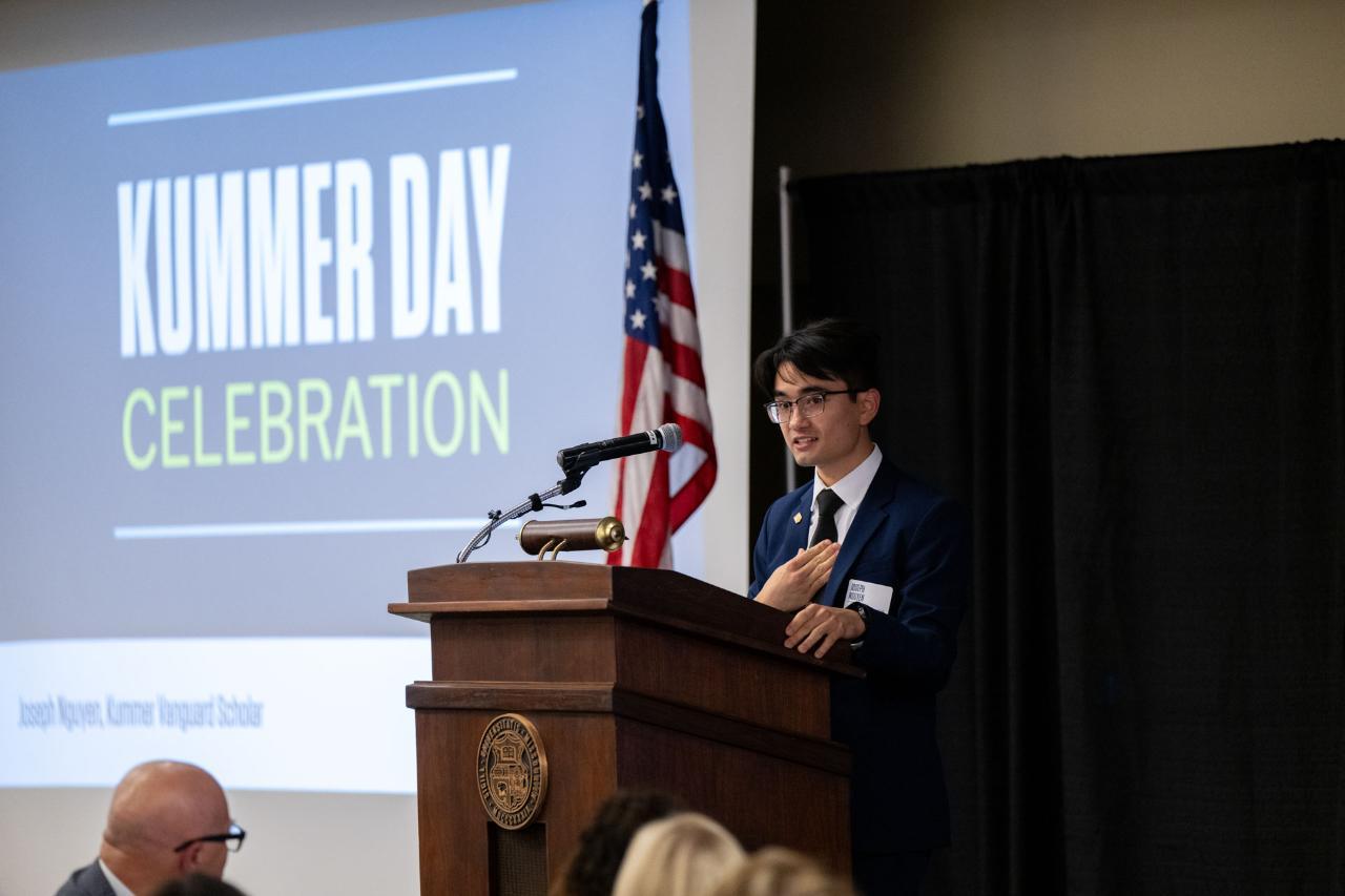 A student stands at a podium speaking.