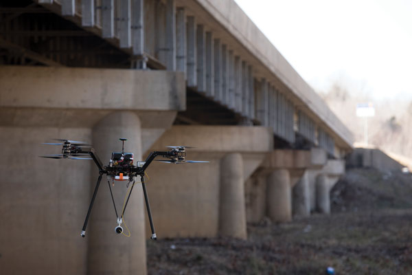 drone flying below a bridge