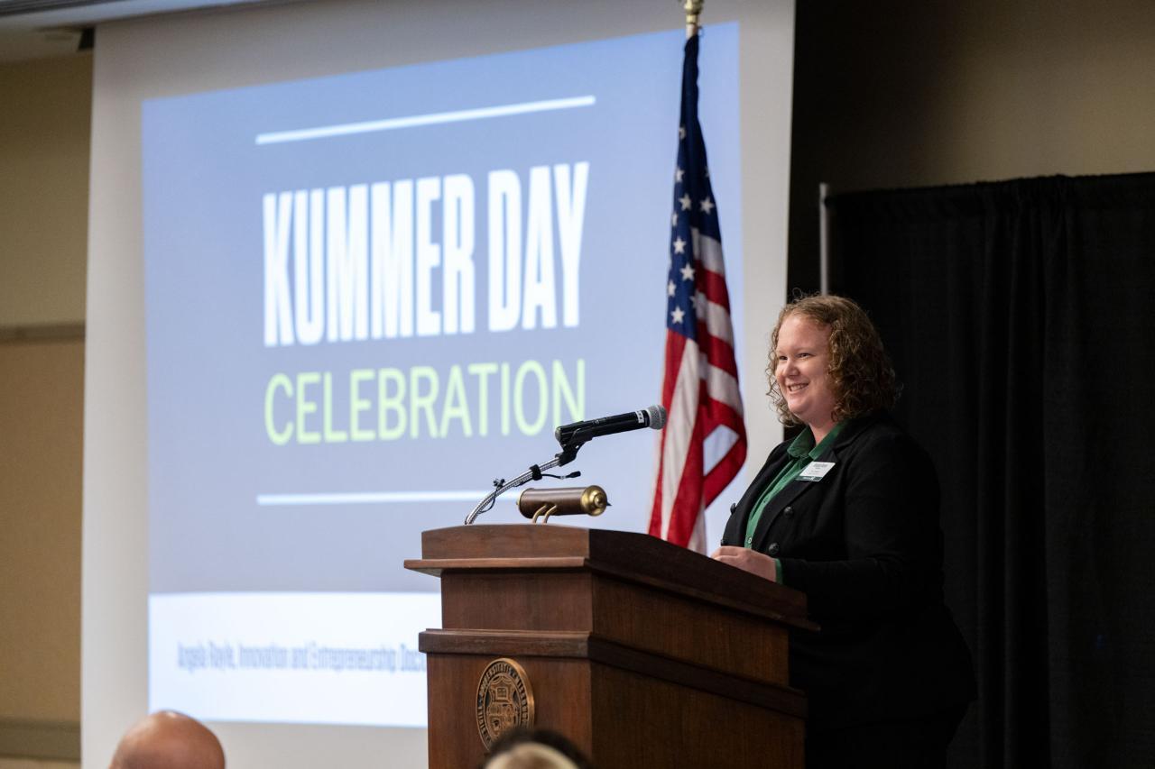 A student stands at a podium speaking during Kummer Day luncheon.